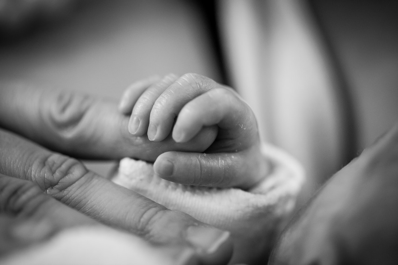 grayscale photo of baby holding parent finger