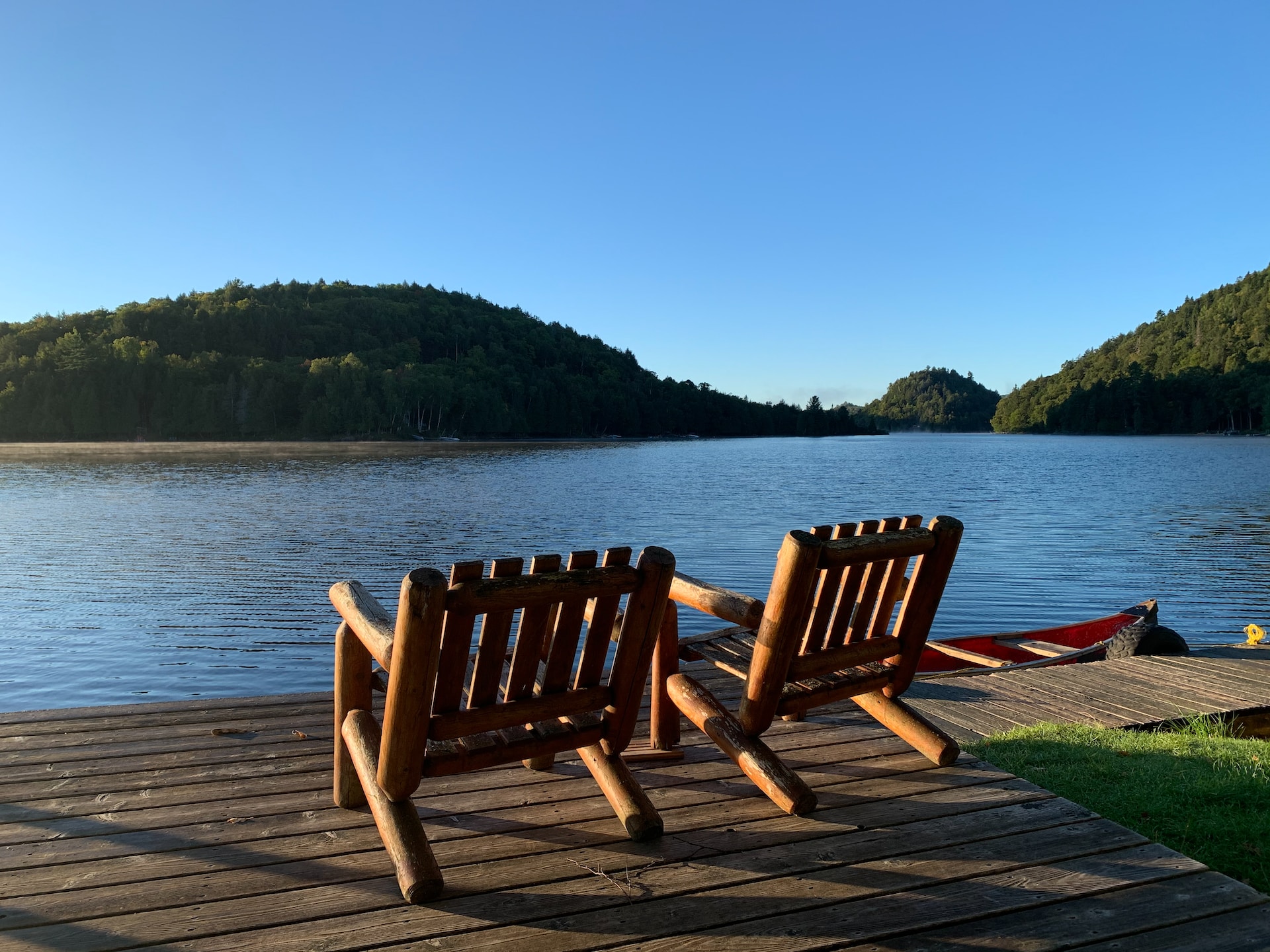 dock with brown wooden armchairs overlooking lake and mountains
