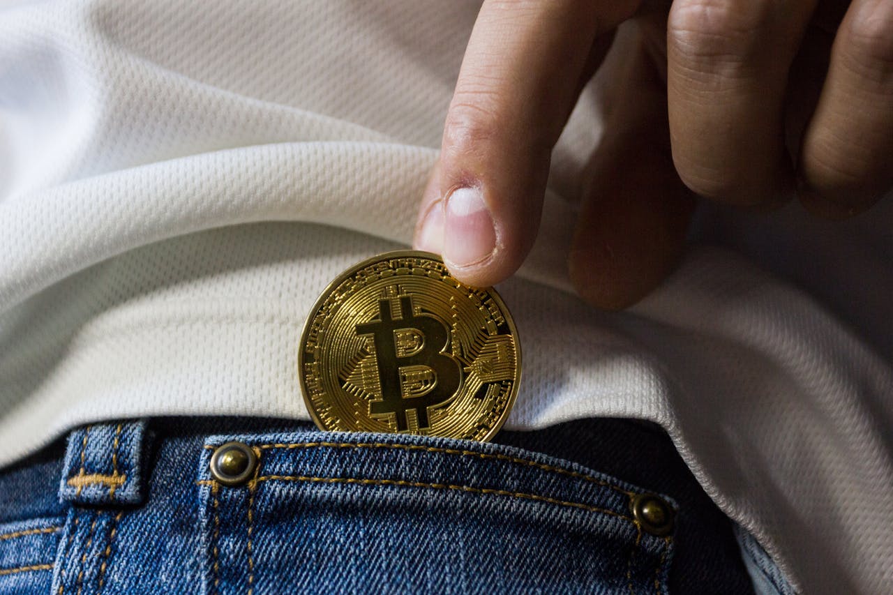 Photo of person putting a bitcoin in their pocket representing crypto-exchange registration requirements in Canada